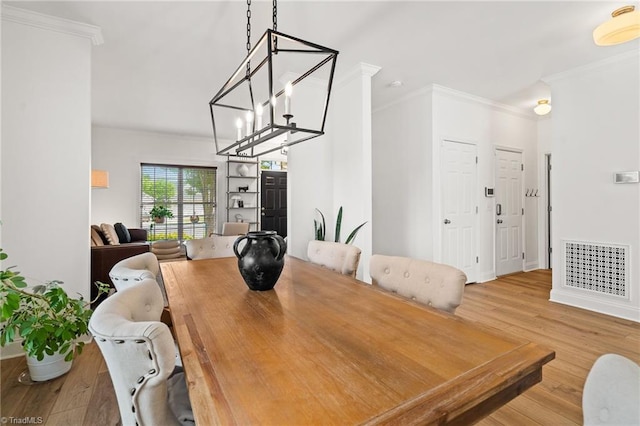 dining space with an inviting chandelier, ornamental molding, wood finished floors, and visible vents