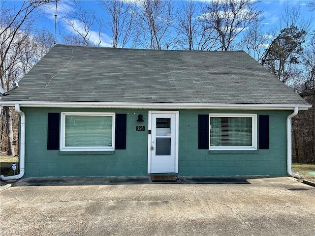 view of front of house with concrete block siding and roof with shingles