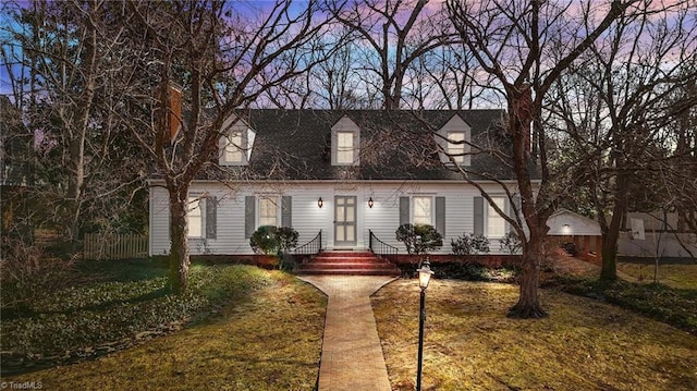 new england style home featuring a lawn