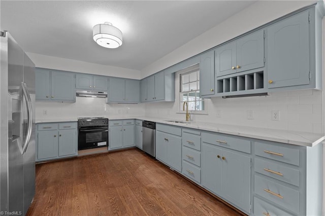 kitchen with dark wood-style floors, a sink, stainless steel appliances, under cabinet range hood, and backsplash