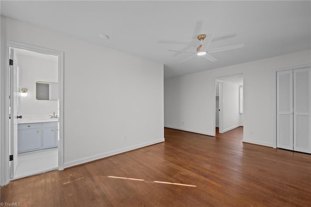 spare room featuring a ceiling fan, wood finished floors, baseboards, and a sink