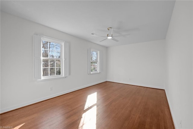 unfurnished room featuring a ceiling fan, wood finished floors, and baseboards