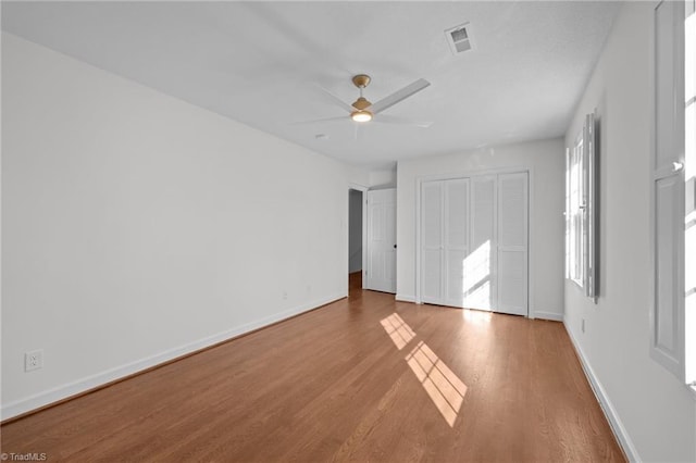 unfurnished bedroom with a ceiling fan, wood finished floors, visible vents, and baseboards