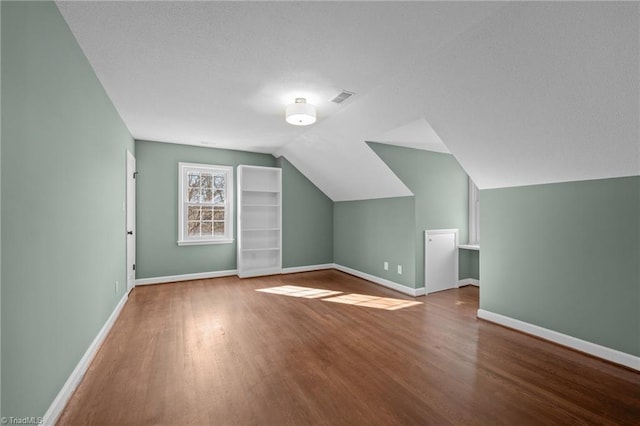 bonus room featuring vaulted ceiling, wood finished floors, visible vents, and baseboards