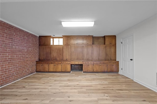 basement with light wood-style flooring, brick wall, and crown molding