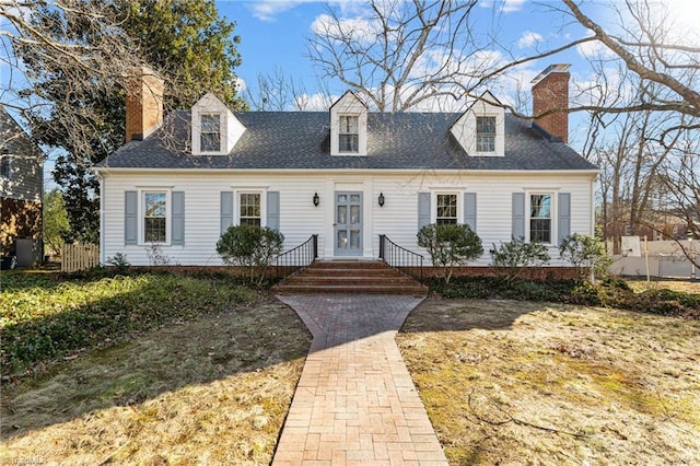 cape cod home with a chimney, roof with shingles, and fence