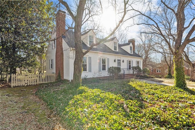 cape cod home with fence and a chimney