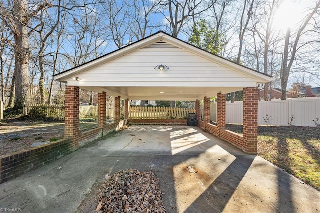 view of parking / parking lot with concrete driveway and fence