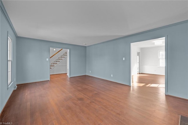 interior space with baseboards, wood finished floors, stairs, and ornamental molding