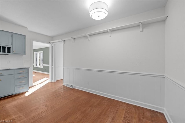 unfurnished dining area featuring wood finished floors, visible vents, and wainscoting