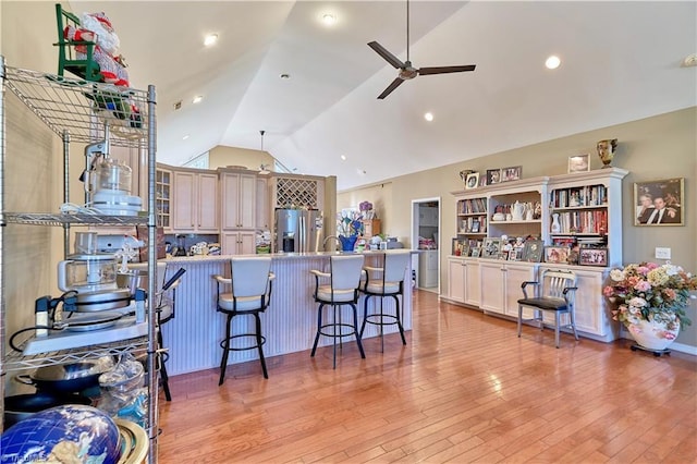 kitchen with stainless steel refrigerator with ice dispenser, a kitchen breakfast bar, ceiling fan, and vaulted ceiling