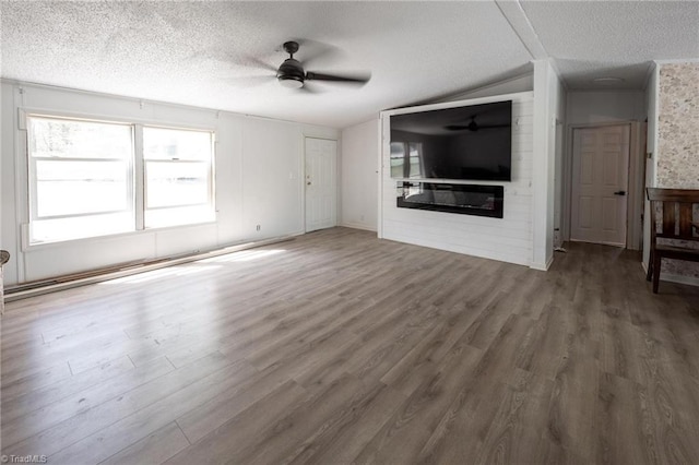 179 Abington Ln, Troutman, NC 28166 - unfurnished living room with a textured ceiling, ceiling fan, wood finished floors, vaulted ceiling, and a glass covered fireplace