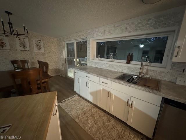 179 Abington Ln, Troutman, NC 28166 - kitchen featuring stainless steel dishwasher, dark wood-style floors, a chandelier, white cabinets, and tasteful backsplash