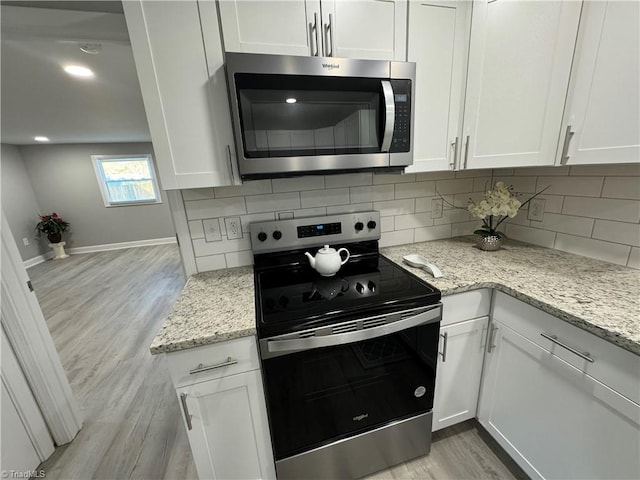 kitchen with light stone countertops, white cabinets, light hardwood / wood-style flooring, and stainless steel appliances