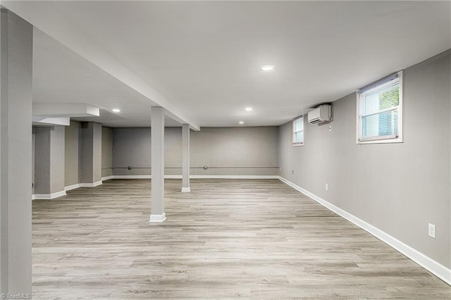 basement with a wall mounted AC and light wood-type flooring