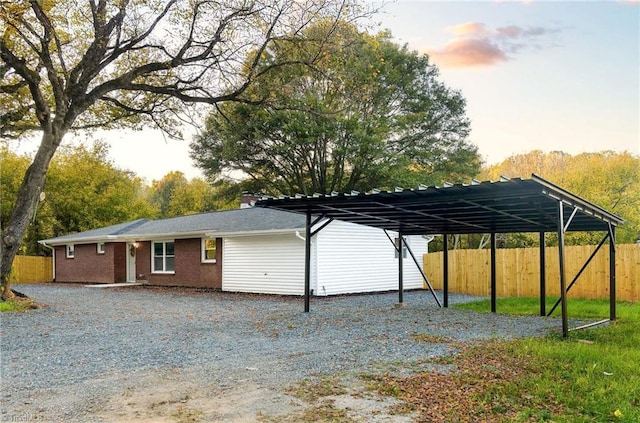 5515 Bethania Rd, Pfafftown, NC 27040 - view of side of property featuring gravel driveway, fence, a carport, and a chimney