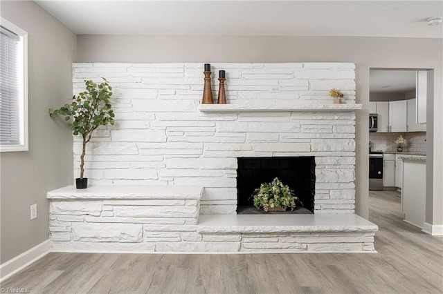 details with a stone fireplace, hardwood / wood-style floors, stainless steel appliances, and backsplash