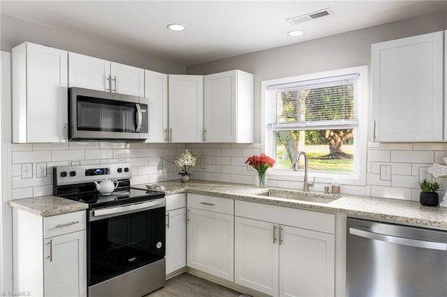 5515 Bethania Rd, Pfafftown, NC 27040 - kitchen featuring stainless steel appliances, a sink, white cabinetry, decorative backsplash, and light stone countertops