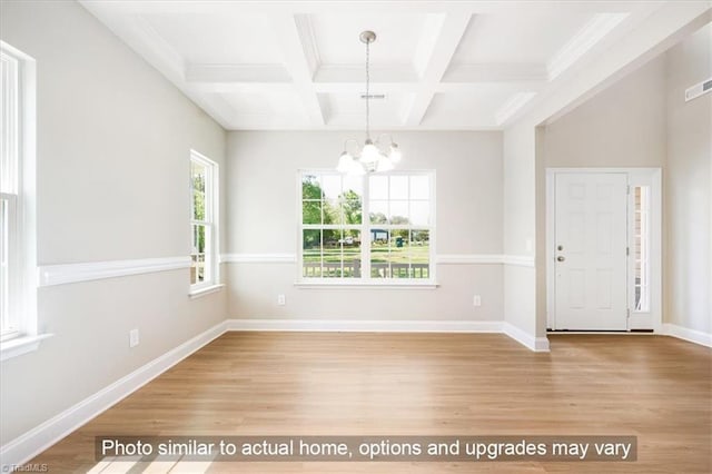 unfurnished dining area featuring beam ceiling, coffered ceiling, wood finished floors, an inviting chandelier, and baseboards