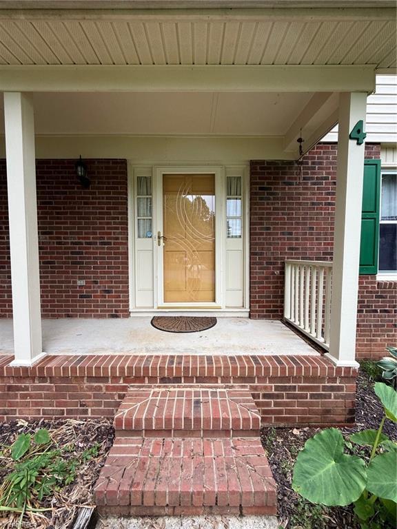 4 Frostbrook Ct, Greensboro, NC 27455 - doorway to property featuring brick siding and a porch