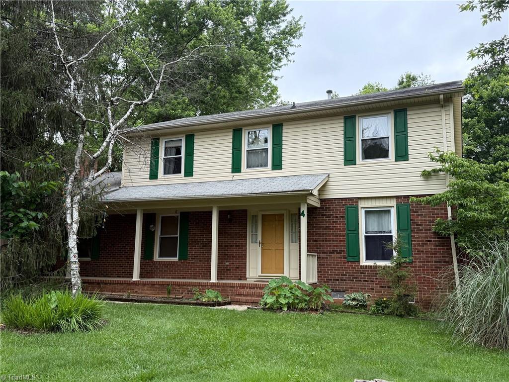4 Frostbrook Ct, Greensboro, NC 27455 - view of front of home featuring brick siding, a front lawn, and covered porch