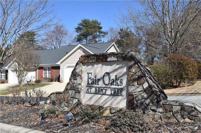 community / neighborhood sign featuring driveway and an attached garage