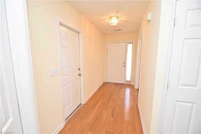 hall featuring light wood-type flooring and baseboards