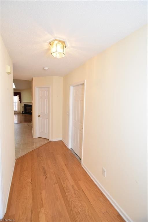 hall featuring light wood-style floors and baseboards