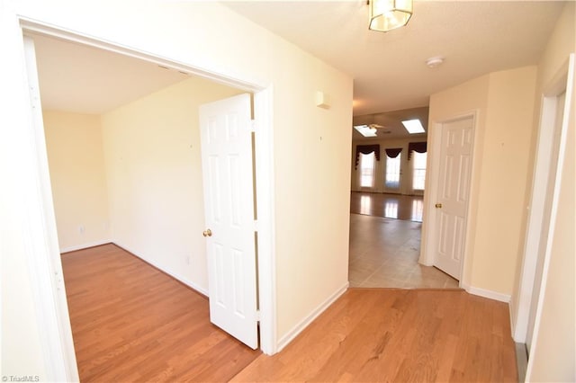 corridor featuring light wood-style floors and baseboards