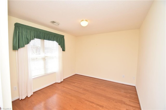 empty room featuring visible vents, light wood-style flooring, and baseboards