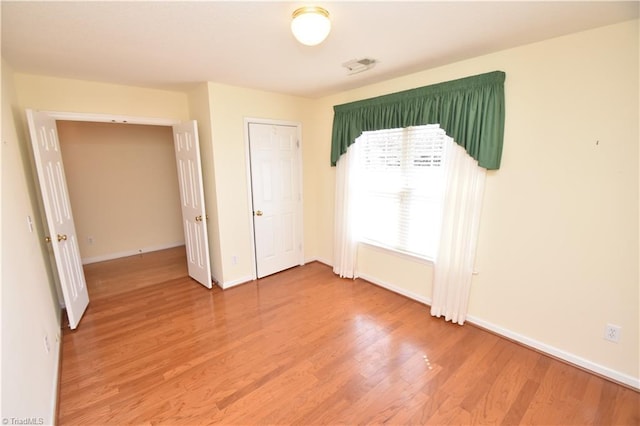 unfurnished bedroom featuring light wood finished floors, visible vents, and baseboards