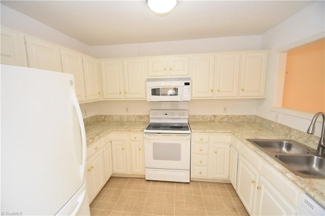 kitchen with white appliances, white cabinetry, light countertops, and a sink