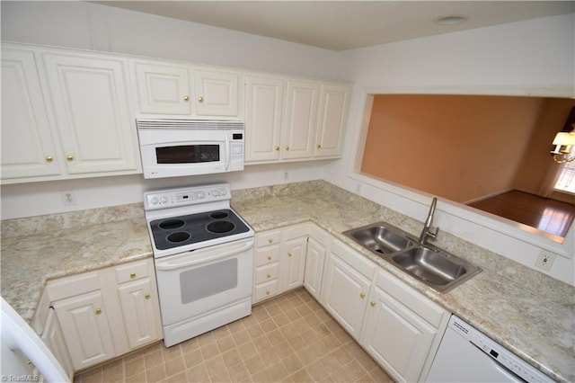 kitchen with white appliances, white cabinets, and a sink