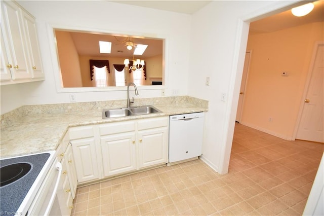 kitchen with white appliances, a skylight, light countertops, white cabinetry, and a sink