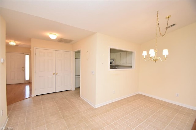 empty room featuring baseboards, visible vents, and a chandelier