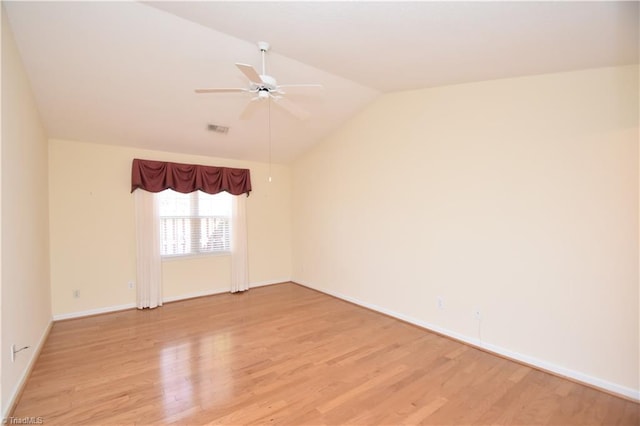 empty room with visible vents, a ceiling fan, vaulted ceiling, baseboards, and light wood finished floors