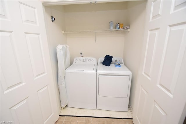 washroom featuring laundry area, washing machine and clothes dryer, and light tile patterned floors