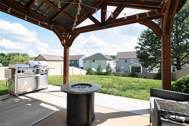 view of patio featuring area for grilling, fence, a residential view, a fire pit, and a gazebo