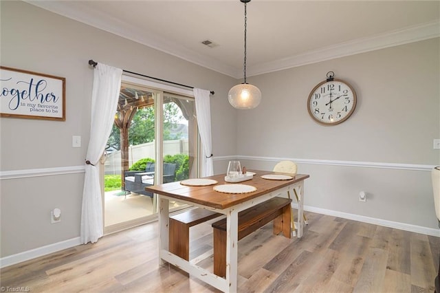 dining room with light wood-type flooring, baseboards, visible vents, and crown molding