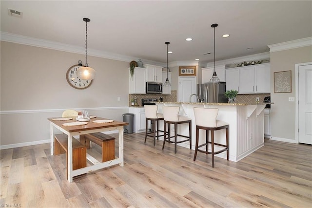 kitchen with tasteful backsplash, visible vents, white cabinetry, and stainless steel appliances