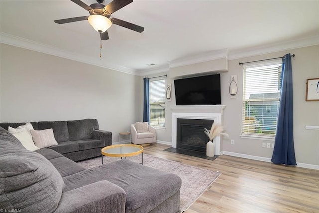 living room with a fireplace with flush hearth, light wood-style flooring, ornamental molding, and a healthy amount of sunlight