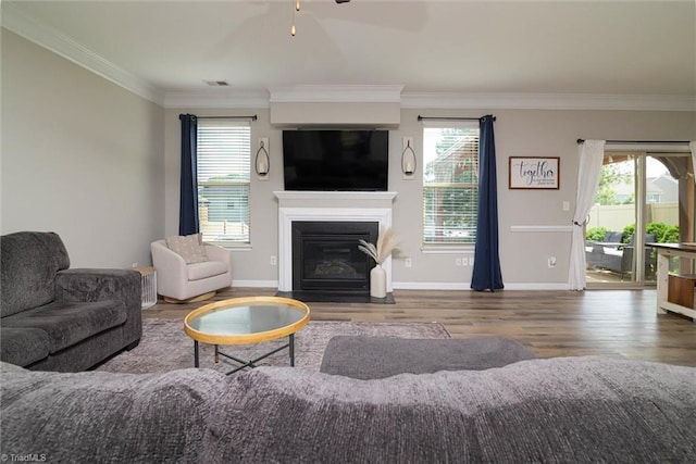 living room featuring wood finished floors, ornamental molding, and a healthy amount of sunlight