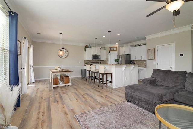 living room with recessed lighting, light wood-style flooring, a ceiling fan, and ornamental molding