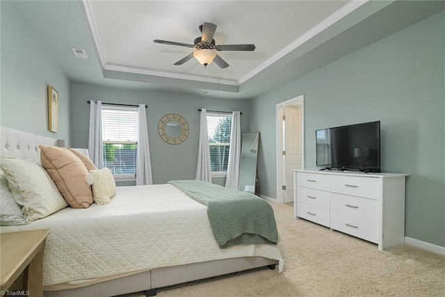 bedroom featuring light carpet, a tray ceiling, baseboards, ornamental molding, and visible vents