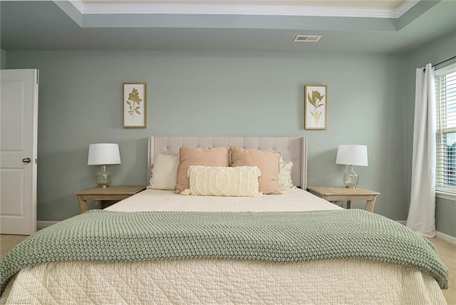 carpeted bedroom featuring baseboards, crown molding, visible vents, and a raised ceiling