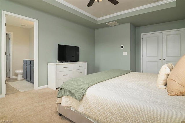 bedroom featuring a closet, light carpet, baseboards, ensuite bath, and ornamental molding