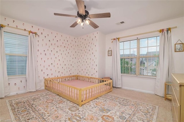 carpeted bedroom featuring wallpapered walls, visible vents, baseboards, and ceiling fan