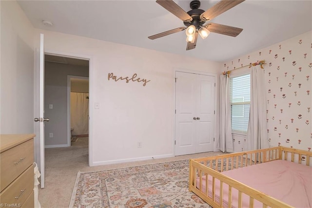 bedroom with wallpapered walls, light carpet, a closet, baseboards, and ceiling fan