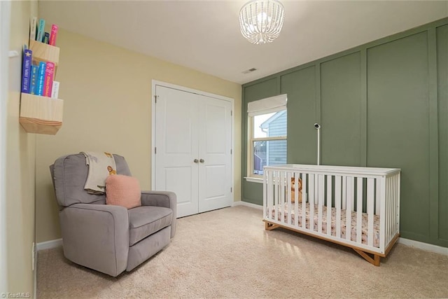 bedroom featuring a chandelier, baseboards, a crib, and light colored carpet