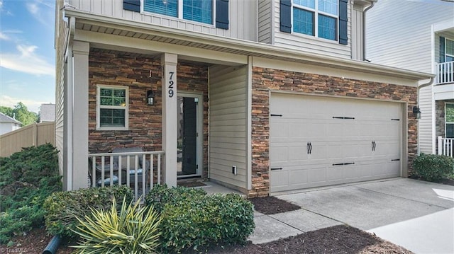entrance to property featuring an attached garage, a porch, stone siding, and board and batten siding
